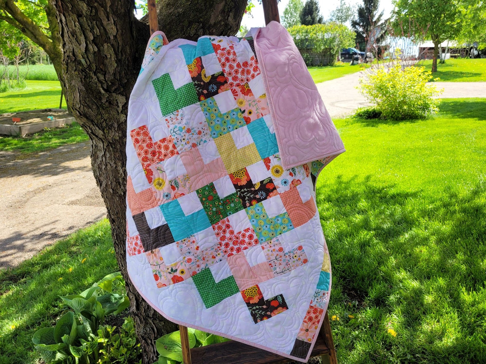baby quilt shown ourdoors under a tree