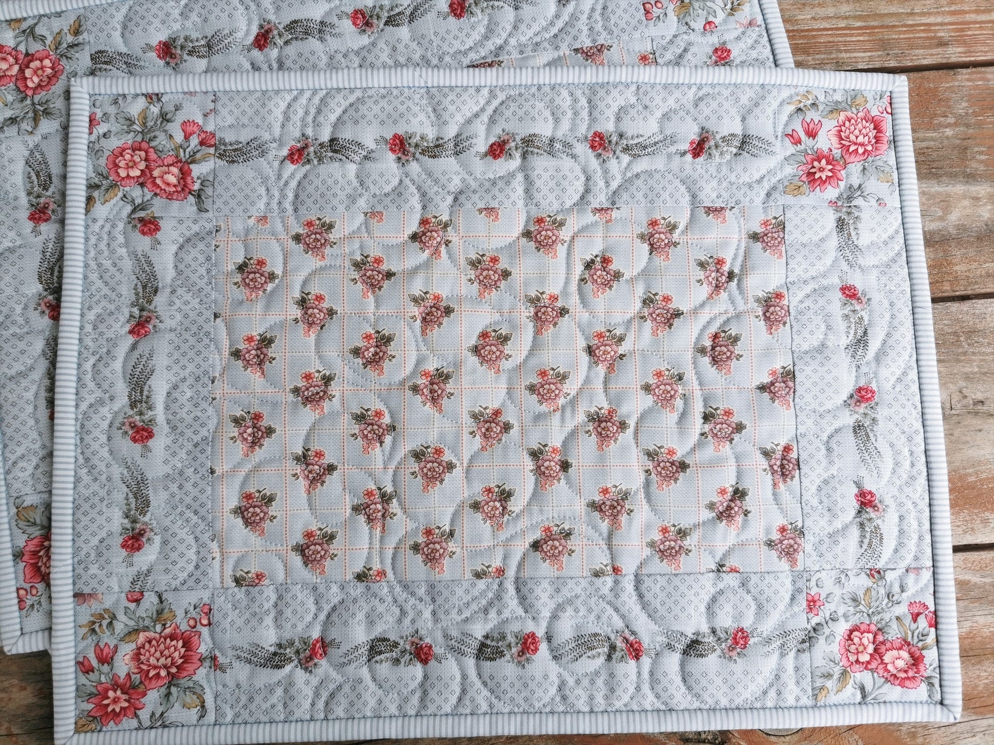 The entire quilted placemat is is shown close up to highlight the fabrics and floral motif quilting.